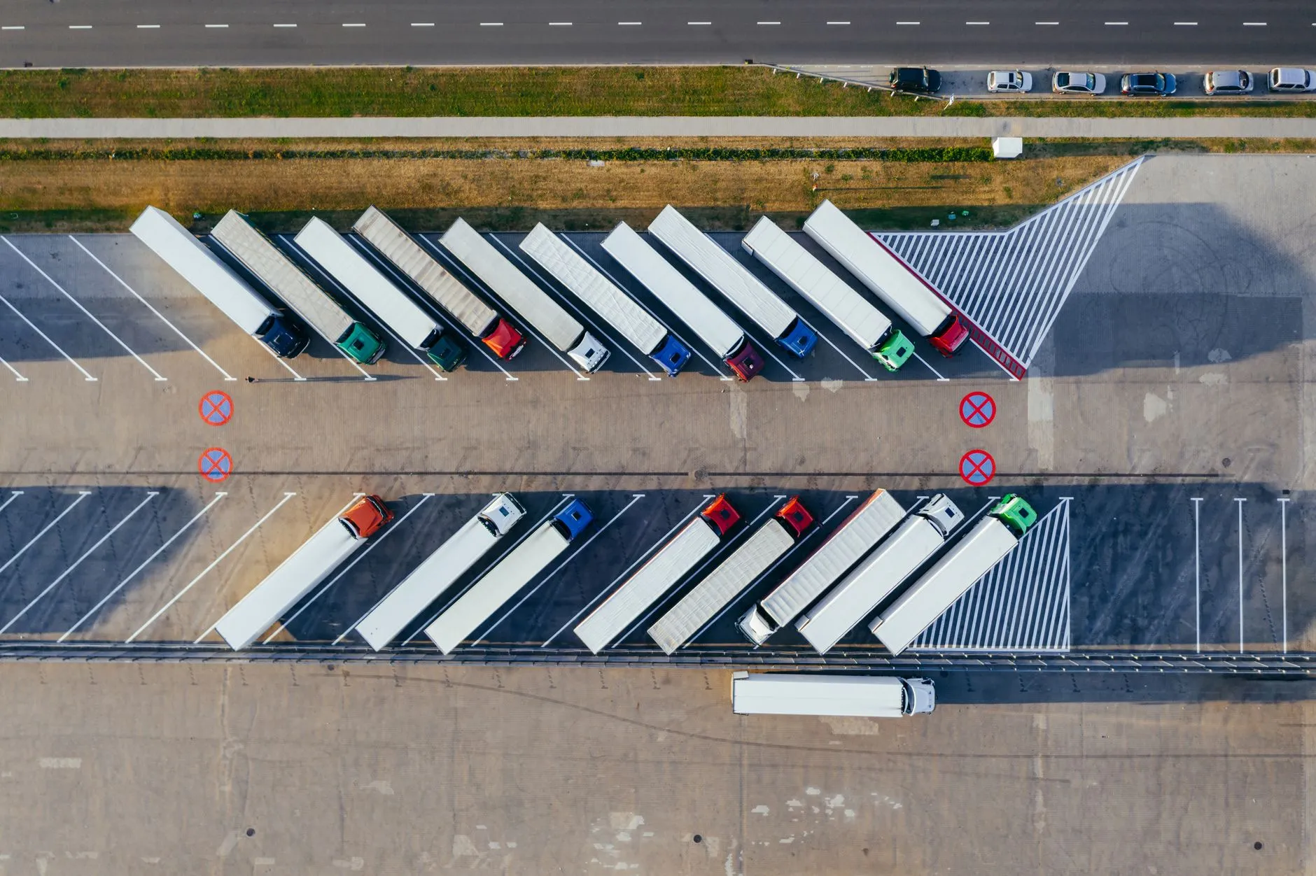 Vista aérea de camiones articulados aparcados en filas en una zona de estacionamiento logística.