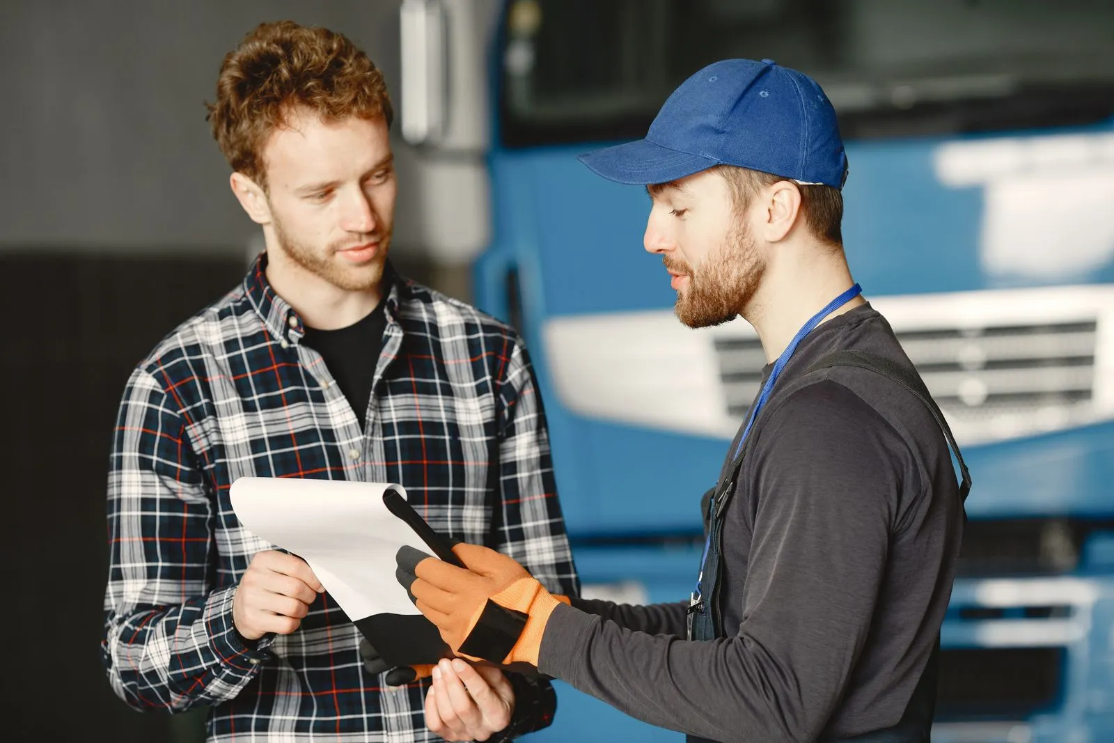 Dos trabajadores del transporte revisando un documento junto a un camión