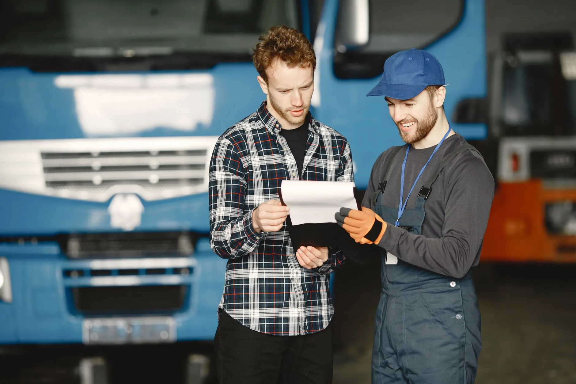 Dos trabajadores del transporte revisando un documento de papel frente a un camión